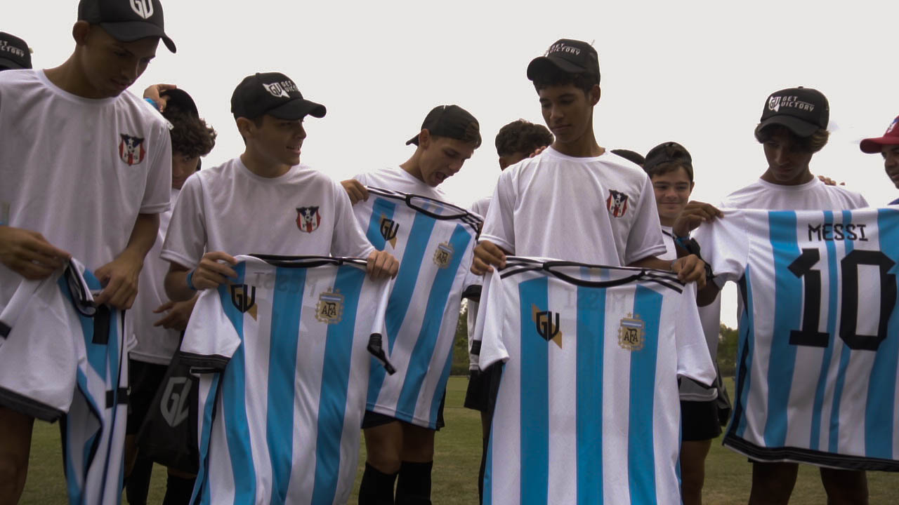 Un entrenador dando indicaciones tácticas a un grupo de futbolistas jóvenes